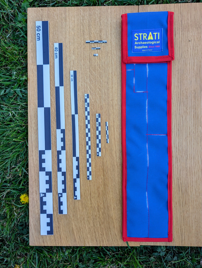 Load image into Gallery viewer, CAMA 50 cm black and white archaeological photo scale set with STRATI blue and red case on wood and grass