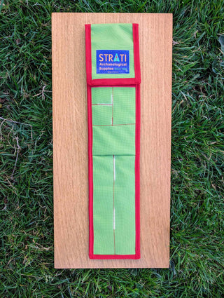 Chargez l'image dans la visionneuse de la galerie, Closed CANOMA 50 cm green and red STRATI carrying case for archaeological photo-scale kit on wood over grass