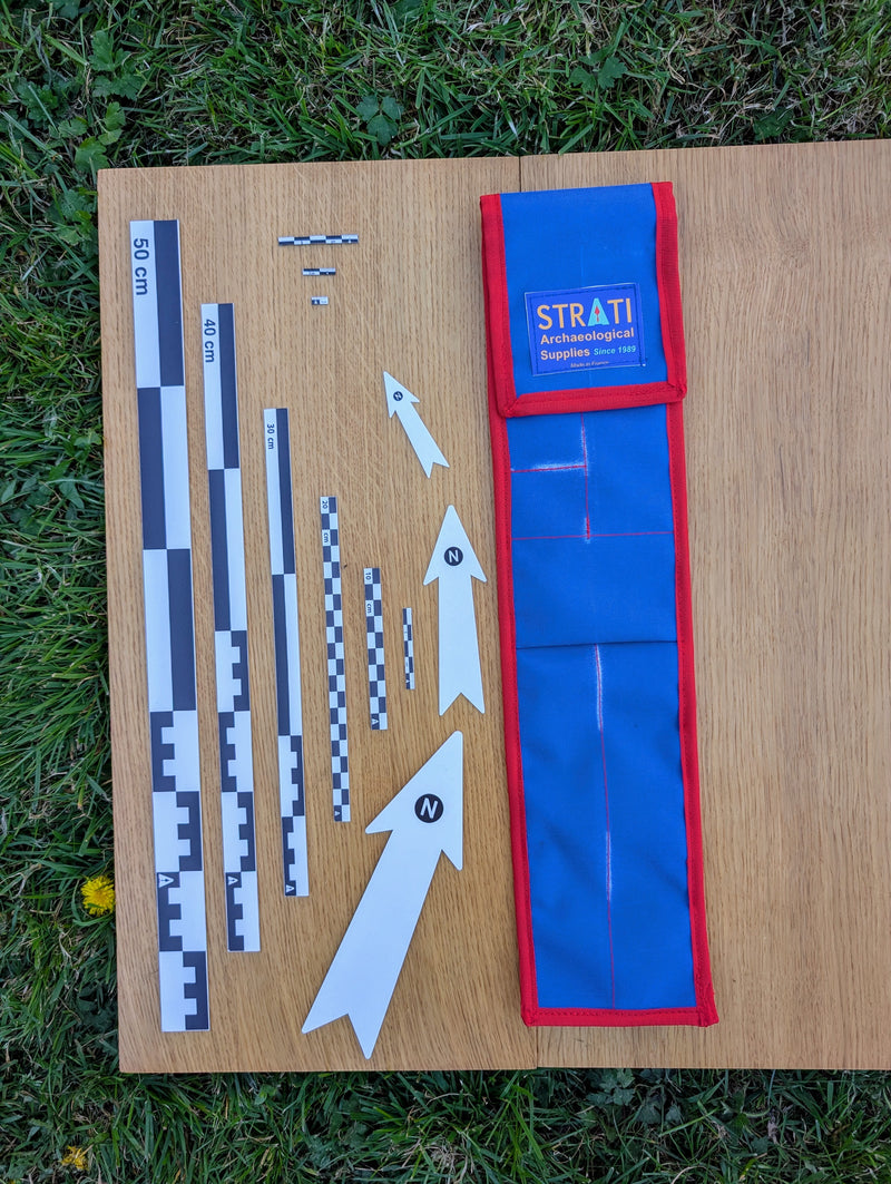 Load image into Gallery viewer, CANOMA 50 cm black-white archaeological scale set with north arrows and open blue-red case on wood and grass