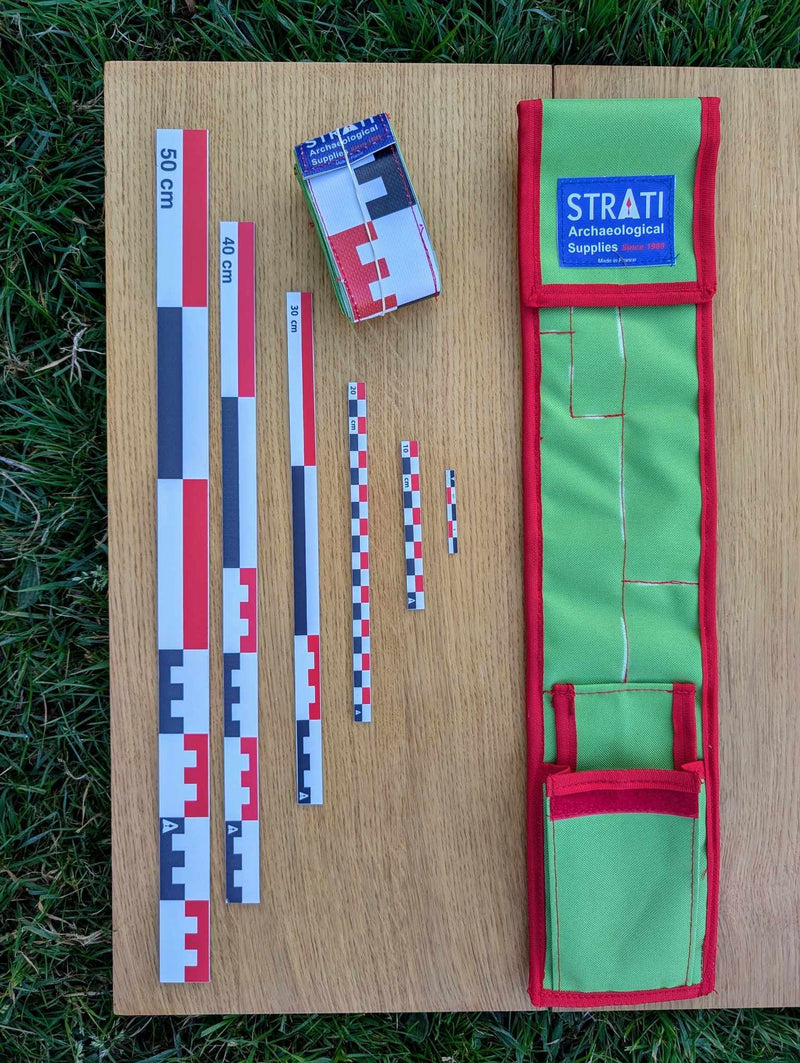 Load image into Gallery viewer, Open CASE 50 cm canvas archaeological scale kit with green red case and red black white metric rulers on wood and grass