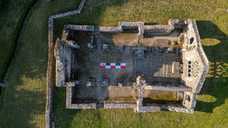 Chargez l'image dans la visionneuse de la galerie, Aerial drone photo of stone ruin foundations in a grassy field with a 5m CANVAS photo scale bar in red-white-black placed at the center for size reference.