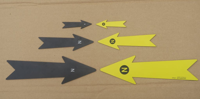 Load image into Gallery viewer, Black and yellow archaeological north arrows in multiple sizes with N markers on a cardboard background