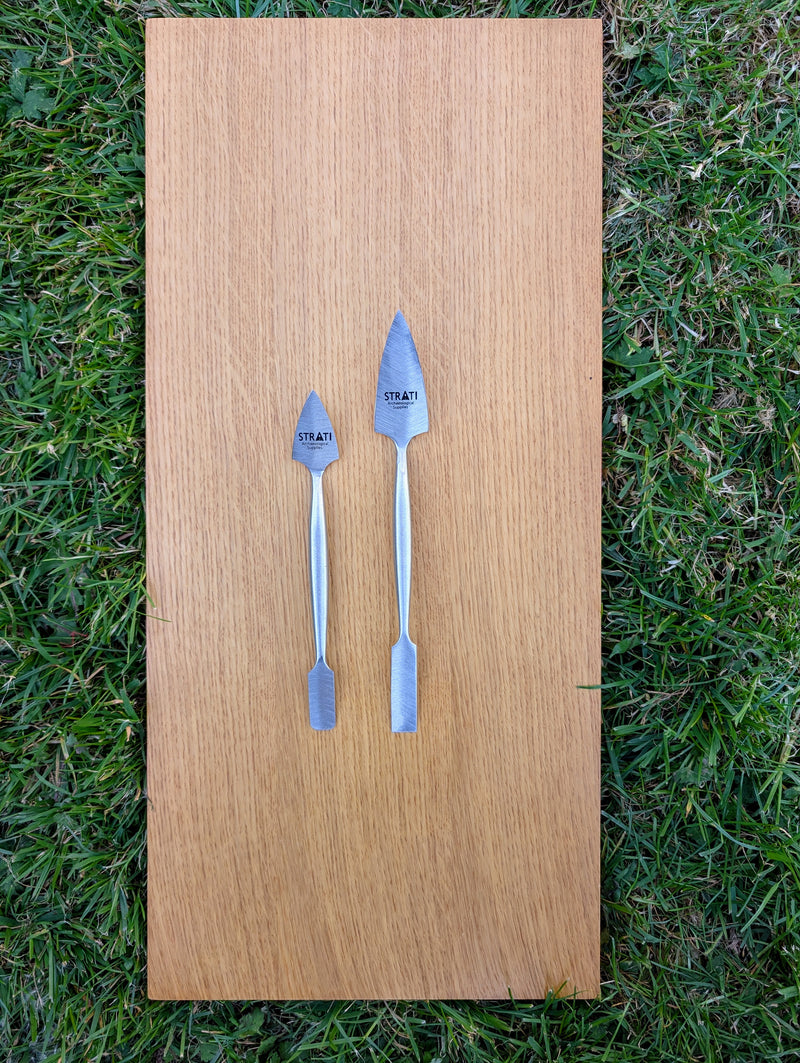 Load image into Gallery viewer, Two forged stainless steel spatulas, small and large, with pointed and flat ends on wood over grass