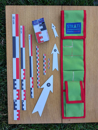 Chargez l'image dans la visionneuse de la galerie, Open CANO 50 cm canvas archaeological scale kit with green red case, metric rulers and white north arrows on wood and grass
