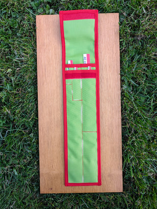 Chargez l'image dans la visionneuse de la galerie, Open green STRATI fabric carrying case with red trim for archaeology photo scales, laid flat on wood over grass
