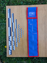 Black and white CASE 50 cm archaeological photo scale set with blue and red carrying case on wood and grass