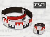Flexible 1m CANVAS photo scale tape shown unrolled in a loop and rolled up compactly. White fabric with red and black metric markings. Reverse side is black stitched fabric.