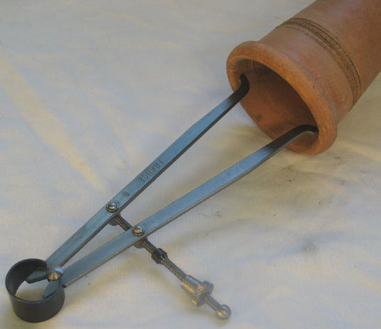 150 mm inside caliper measuring the opening of a terracotta vessel on a light background