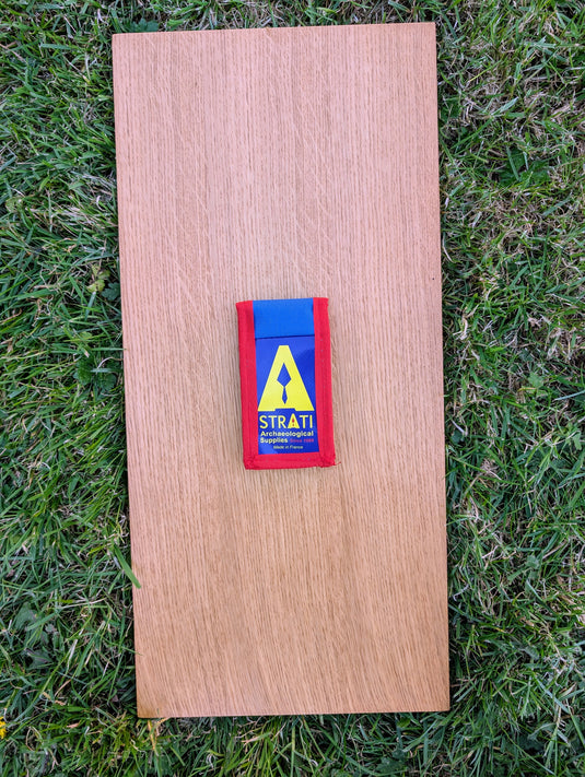 Closed Strati Minimix+ blue and red archaeological pouch with yellow logo on wood over grass