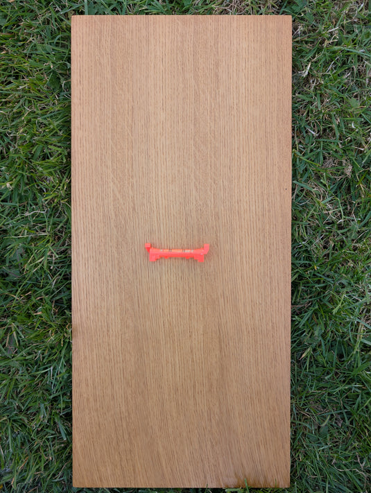 Orange hook leveller on a wooden board for checking horizontal alignment in field documentation
