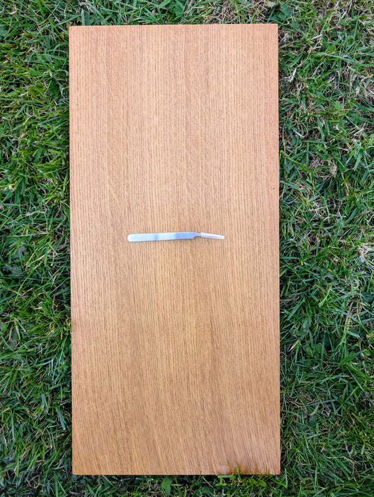 Curved stainless steel precision tweezers on a wooden board for archaeological field and lab work