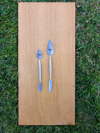 Chargez l'image dans la visionneuse de la galerie, Two forged stainless steel spatulas, small and large, with pointed and flat ends on wood over grass
