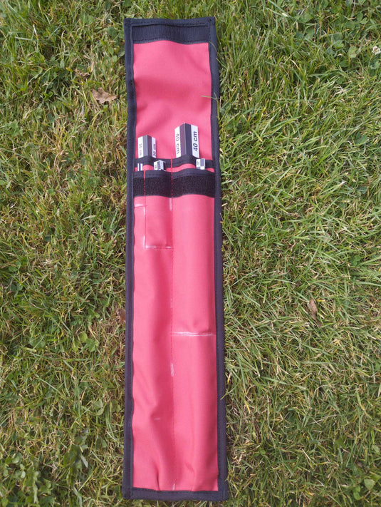 Black and white angular archaeological photo scales in an open red and black fabric holder on grass