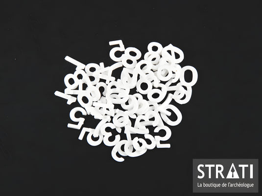 White 12 mm plastic numbers for archaeological letter boards arranged on a black Strati background