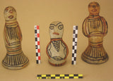 Angular archaeological photo scale (RWB) standing next to painted ceramic figurines on beige background, with BW and BY scales also visible. Made in France.