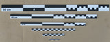 Six black-white flat photo scales from 50cm to 5cm arranged on tan cardboard. High-contrast monochrome set without case.