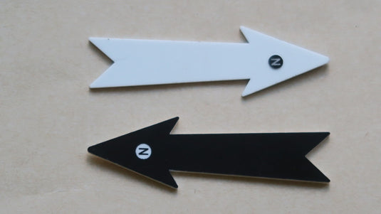 Two 7 cm white and black forked-tail north arrows on beige background