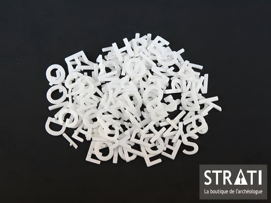 133 white 24 mm plastic alphabet letters and numbers scattered on black background