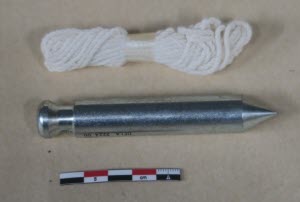 Fil à plomb cylindrique et corde, avec une échelle de référence photographique.